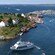 A boat filled with passengers sails through a series of rocky islets dotted with mariners homes